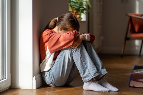 a sad young girl sat on the floor