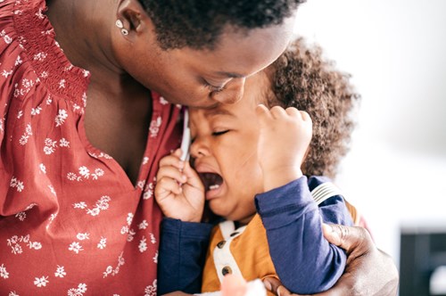 a small child having a tantrum whilst being held by his mother