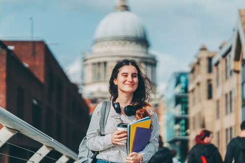 a teenager holding school books, with St Paul's Cathedral in the background