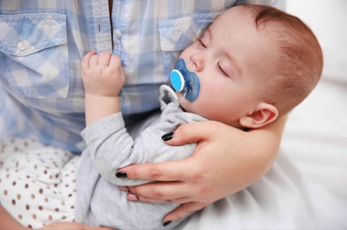 a sleeping baby with a dummy in its mouth