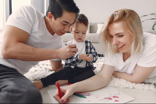 A young man and woman drawing with their child