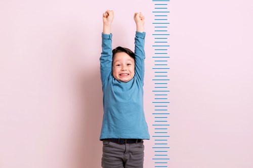 a child stood next to a measuring chart