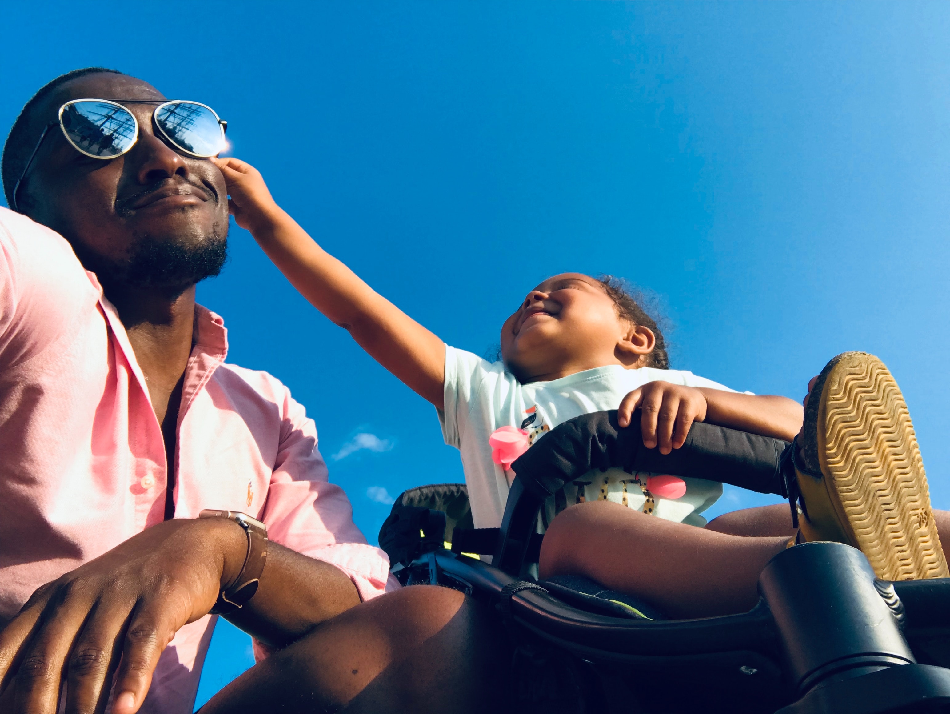 A dad and toddler laughing together in the sunshine