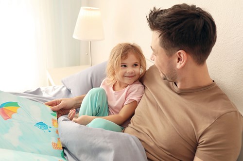 a dad reading a bed time story to his daughter