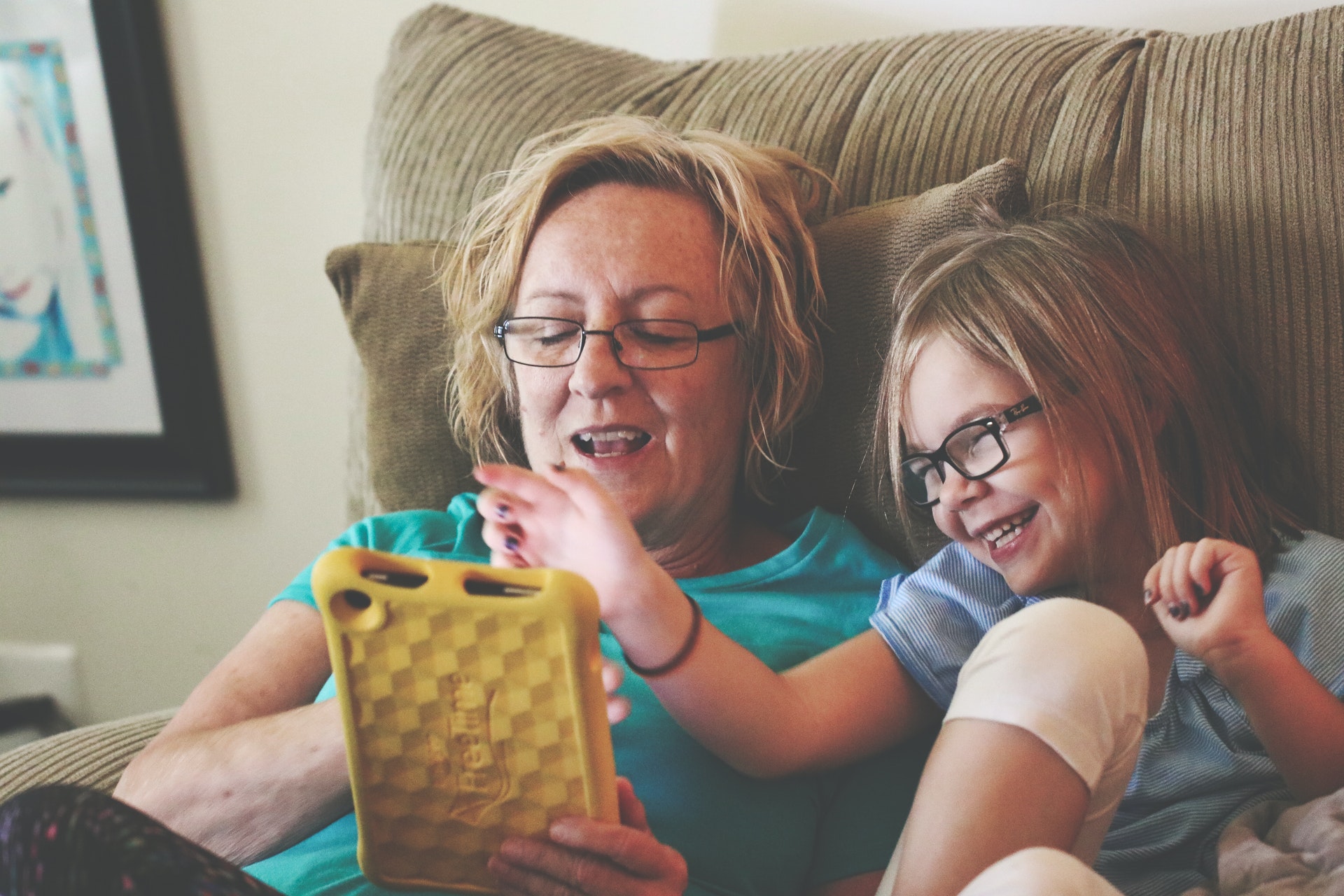 A mother and young daughter using a yellow tablet together